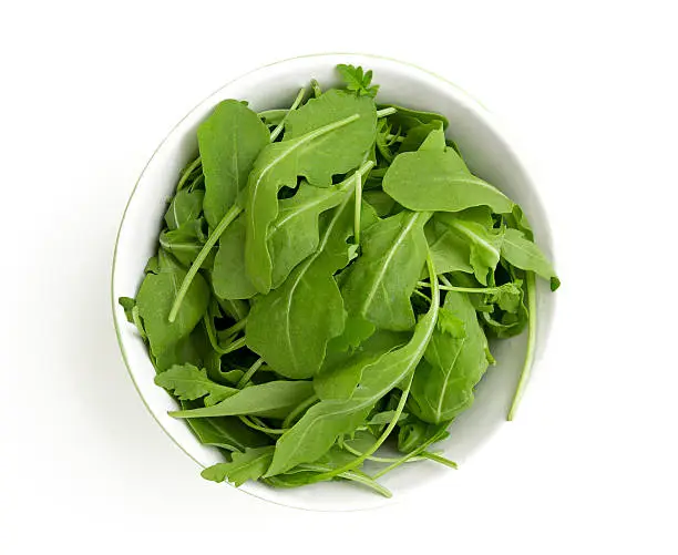 Photo of rucola in a glass bowl isolated on white background