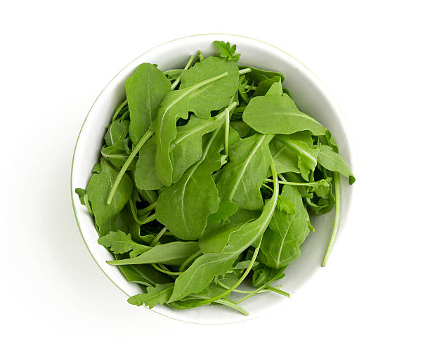 rucola em uma Tigela de vidro isolado sobre fundo branco - fotografia de stock