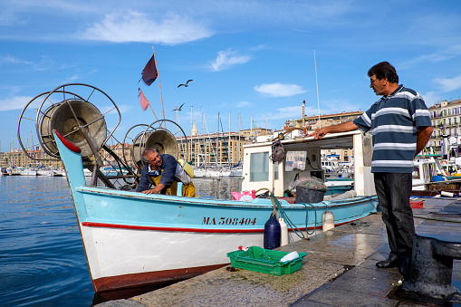 Marseille, France - October 19, 2014: Two fishermen chatting at the Vieux-Port, a main tourist attraction in the french coastal town.