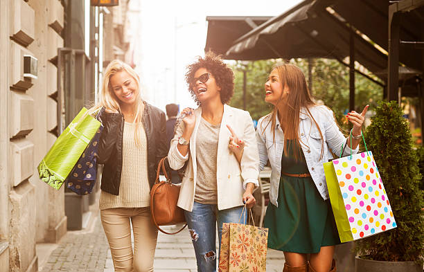 Happy woman in shopping Three attractive young girls holding shopping bags while walking on the street laughing and smiling shopping photos stock pictures, royalty-free photos & images