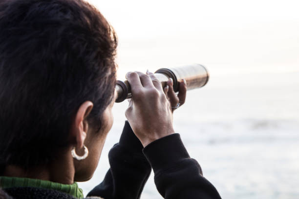 istock Woman with spyglass looking toward ocean 494420688
