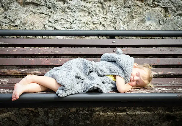 Photo of little girl in fur coat sleeping on the bench