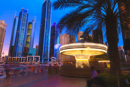 Dubai marina city skyline at night in the rainy evening with long exposure shot of a carousel and rain drops effect.
