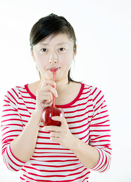 Young asian woman drinking apple juice by a straw.