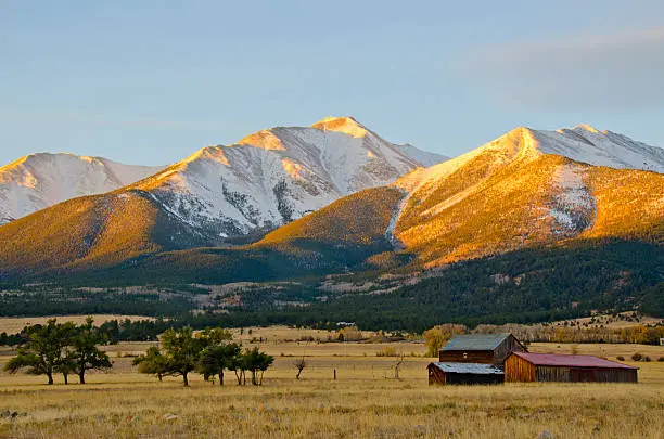 A snow capped Mount Princeton in the Collegiate Peak Range of the Rocky Mountains, overlooks an old ranch at morning's first light.  Late Fall has brought a dusting of snow to this 14,196 foot peak near Buena Vista, Colorado, but the Arkansas River Valley at its base still has barren ranchland and a few turning cottonwood trees.