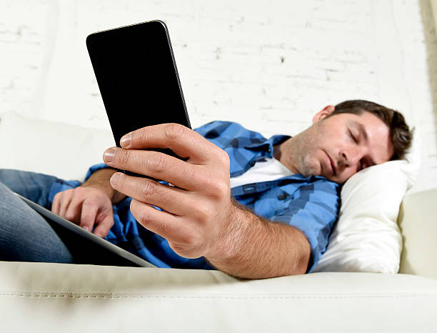 istock man sleeping on couch with mobile phone and digital tablet 494426106