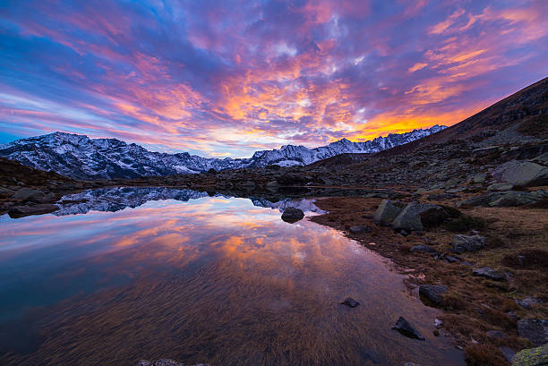 High altitude alpine lake, reflections at sunset High altitude alpine lake in idyllic land once covered by glaciers. Reflection of snowcapped mountain range and scenic colorful sky at sunset. Wide angle shot taken on the Italian Alps at 2200 m asl. ice lakes colorado stock pictures, royalty-free photos & images