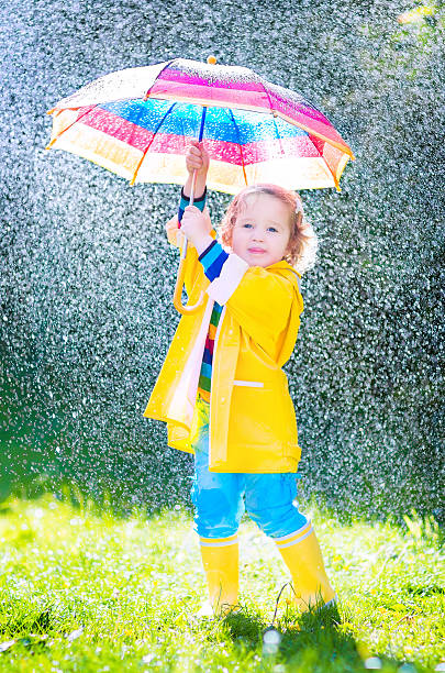 istock Funny toddler with umbrella playing in the rain 494431821