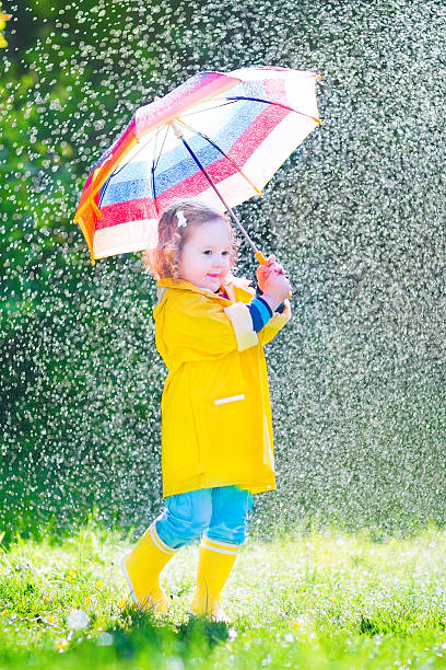 istock Funny toddler with umbrella playing in the rain 494431839