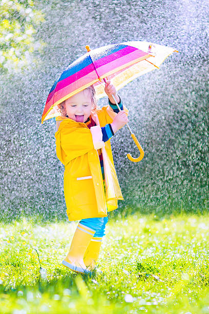 istock Funny toddler with umbrella playing in the rain 494431903