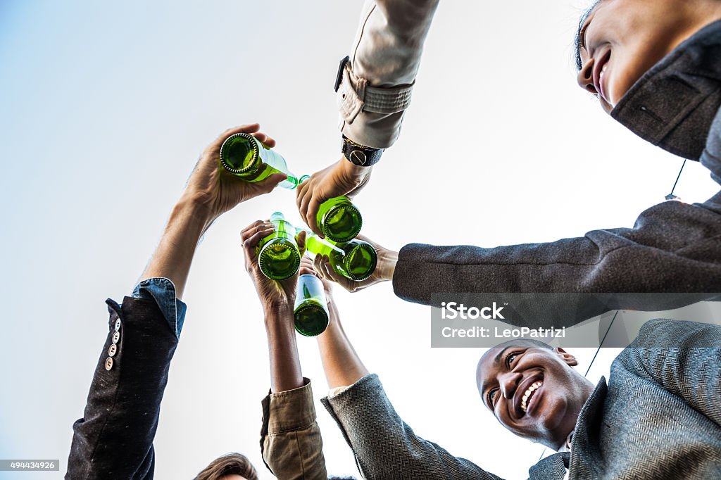 Friends toasting during a party Friends having fun and drinking beers together during a rooftop party in New York East Village. Party - Social Event Stock Photo