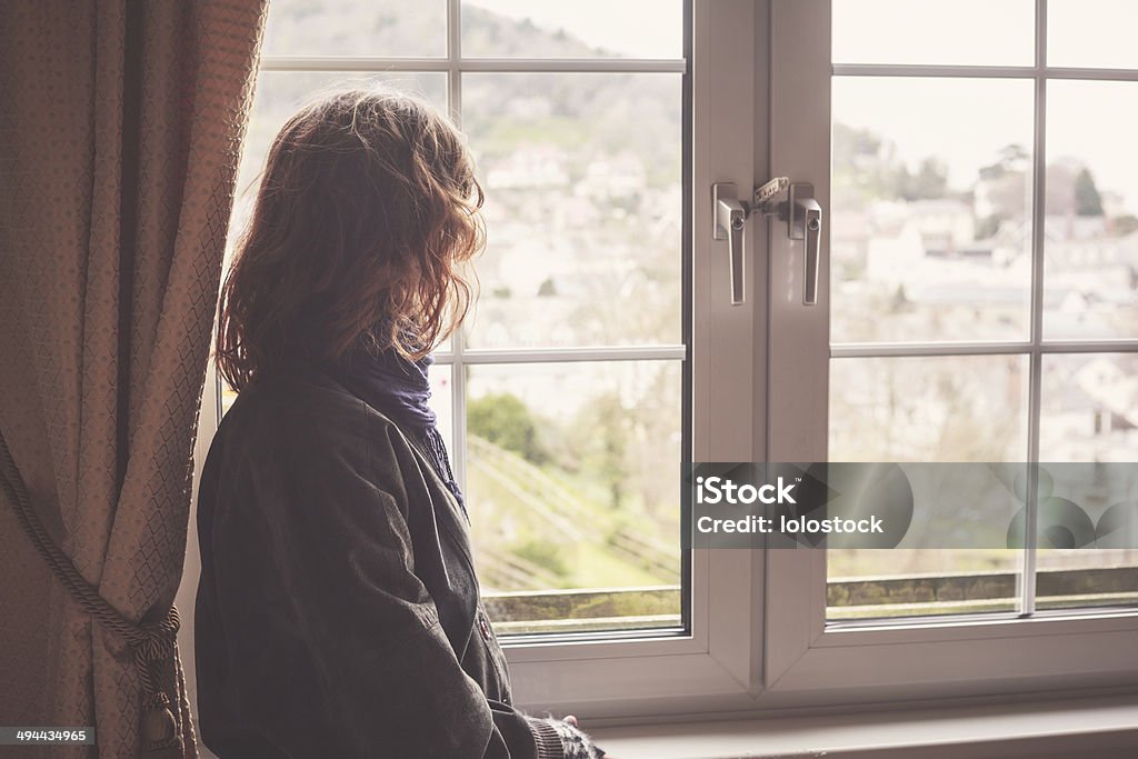Woman looking out the window Young woman is looking out the window Rear View Stock Photo