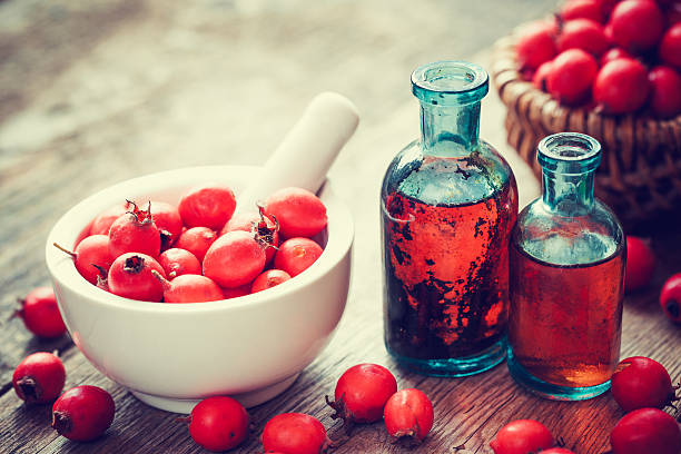 Mortar of hawthorn berries and tincture bottles Mortar of hawthorn berries, two tincture bottles and thorn apples in basket on old wooden table. Herbal medicine. Selective focus. hawthorn stock pictures, royalty-free photos & images