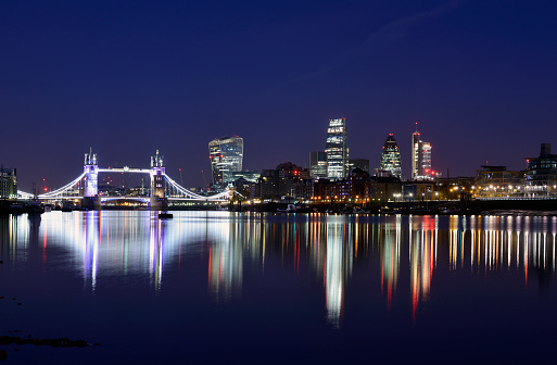 A very early morning picture of the view accross the river Thames in London England. taken on a cold clear morning in October and showing beautiful reflections from some of the most iconic buildings in London including tower bridge.