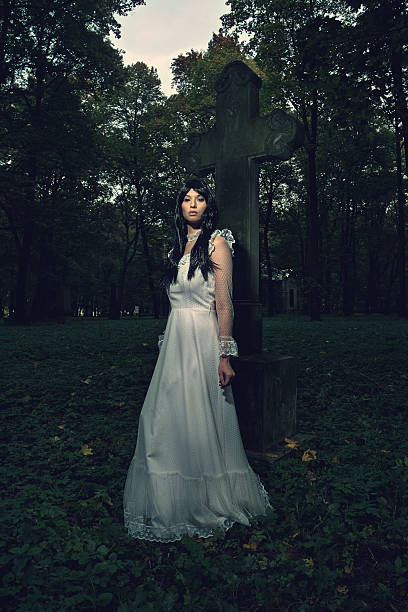 istock Witch from the cemetery, in front of cross 494441568