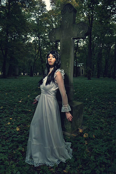 istock Witch from the cemetery, in front of cross 494441590