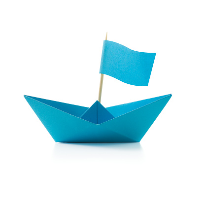 Origami blue paper boat with flag on white background