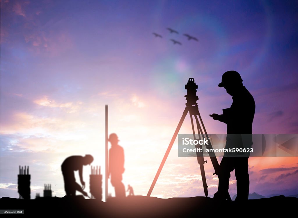 silhouette survey engineer working  in a building site over Blur silhouette survey engineer working  in a building site over Blurred construction worker on construction site Surveyor Stock Photo