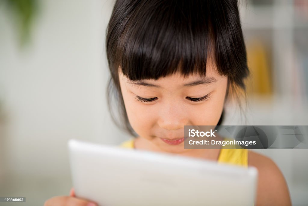 Girl with digital tablet Close-up image of cute little girl using application on digital tablet in her hands 2015 Stock Photo