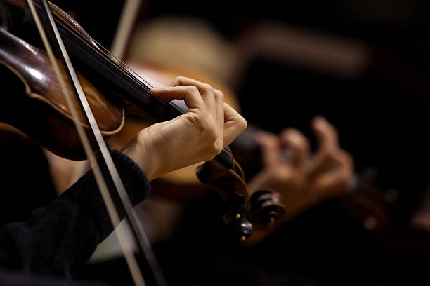 The girl's hand on the strings of a violin The girl's hand on the strings of a violin in dark colors classical music stock pictures, royalty-free photos & images