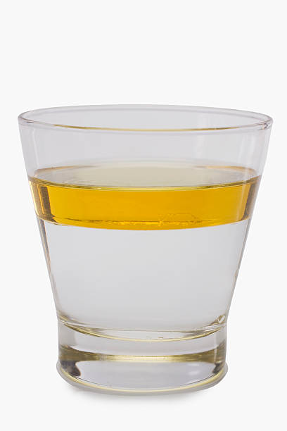 Oil floating on water surface in a glass stock photo
