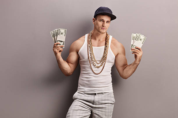 Young male rapper holding money Young male rapper with golden chain around his neck holding few stacks of money and looking at the camera rap stock pictures, royalty-free photos & images