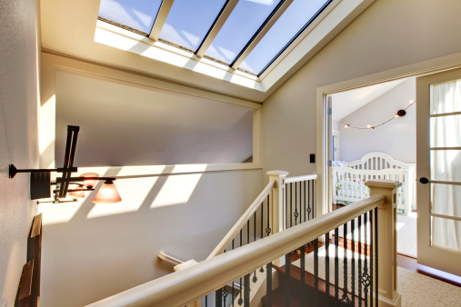 Staircase with skylight and baby room in a bright hallway.