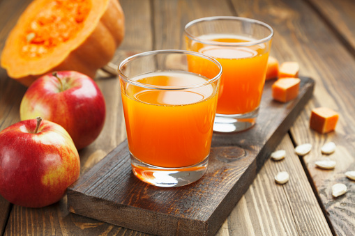 Juice of apples and pumpkins in the glasses on the table