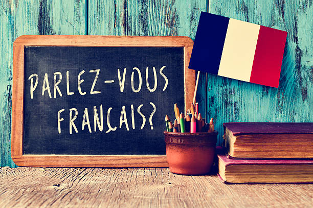 question parlez-vous francais? do you speak french? a chalkboard with the question parlez-vous francais? do you speak french? written in french, a pot with pencils and the flag of France, on a wooden desk french language photos stock pictures, royalty-free photos & images