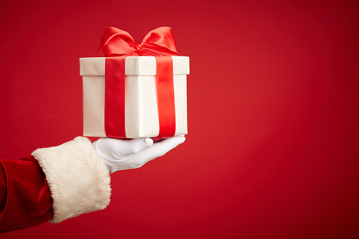Santa hand holding giftbox with surprise