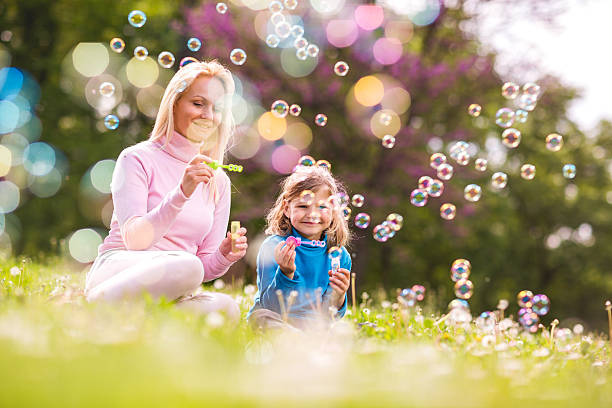istock Smiling mother and daughter blowing bubbles in nature. 494496358