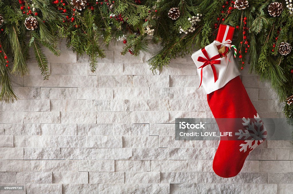 Christmas Stocking Christmas Stocking with gifts and bow hung on a fireplace with evergreen garland. Christmas Stocking Stock Photo