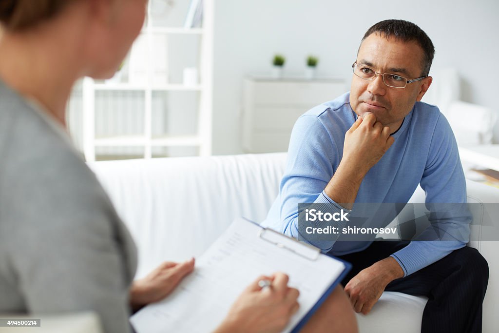 Listening to psychologist Pensive man in eyeglasses listening to psychologist Psychotherapy Stock Photo