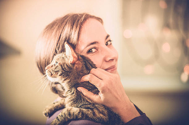 Woman enjoying sunlight with cat on the bed