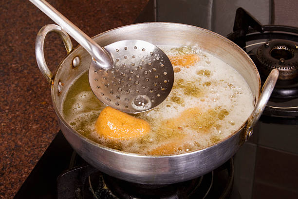 Close-up of pakoras being fried in a pan on a stove stock photo