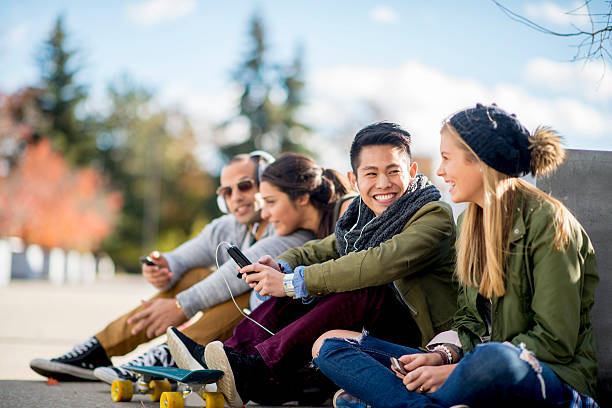 Teenagers Hanging Out In the City A multi-ethnic group of college age students are sitting together texting on their cell phones and taking selfies together. secondary school activities stock pictures, royalty-free photos & images