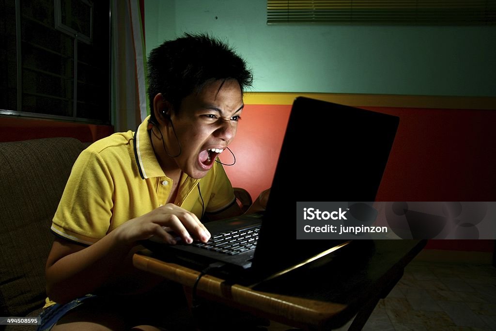 Asian Teen Playing or Working on a Laptop Computer Photo of an asian teen playing or working on a laptop computer Video Game Stock Photo