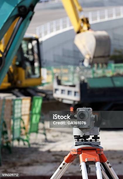 Dumpy Level With Excavator Behind Stock Photo - Download Image Now - 2015, Backhoe, Business Finance and Industry