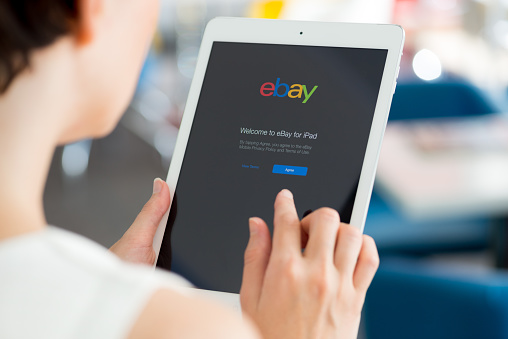 Kiev, Ukraine - May 21, 2014: Woman holding a white Apple iPad Air with eBay welcome message on a screen. eBay is the worldwide online auction and shopping website that founded in September 3, 1995.