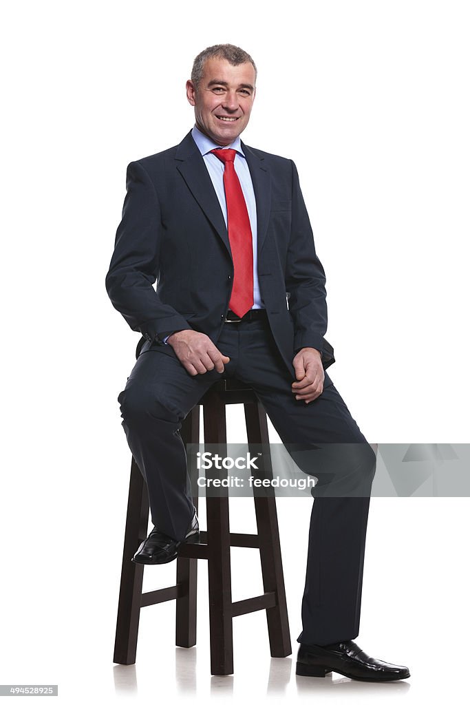 business man on high stool portrait of a middle aged business man sitting on a high stool and smiling for the camera. isolated on a white background Chair Stock Photo