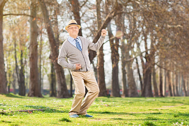 Overjoyed senior playing air guitar outdoors Overjoyed senior playing air guitar in park air guitar stock pictures, royalty-free photos & images