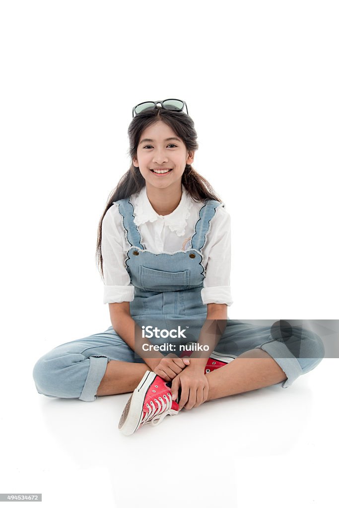 Asian teenage girl smiling and sitting on white background. Asian teenage girl smiling sitting on chair with white background. 2015 Stock Photo