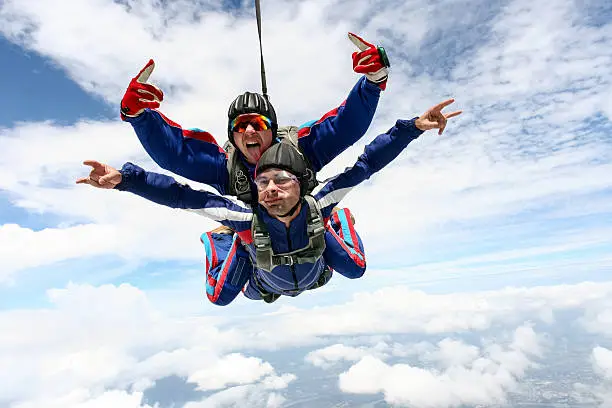 Tandem jump in the sky with clouds.