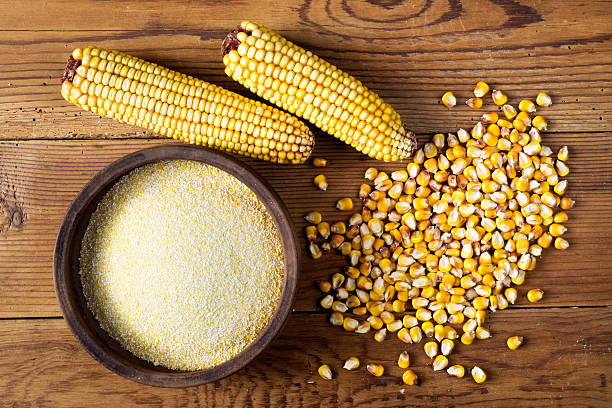 Maize, meal and ceramic bowl on wooden table stock photo