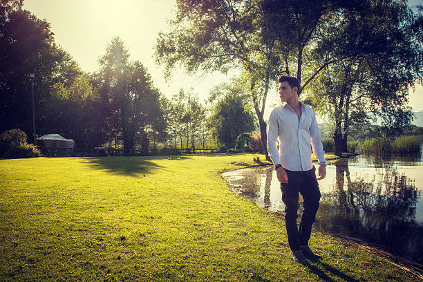 Handsome young man on a lake's shore in a sunny, peaceful day, standing