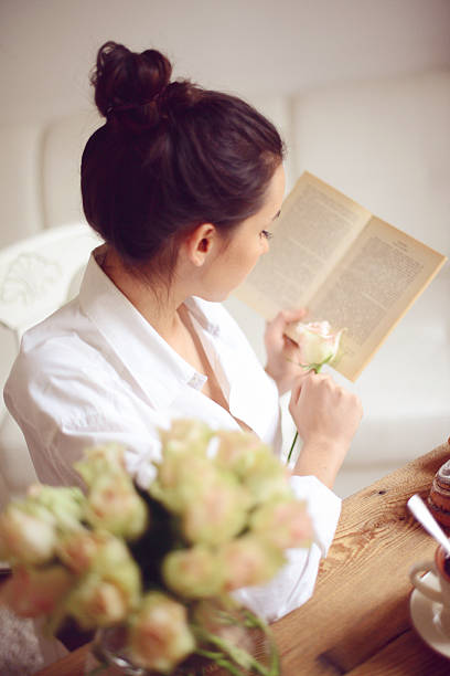 young woman having breakfast and reading a book