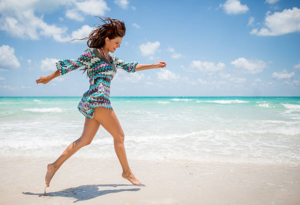 mujer divirtiéndose en la playa - jumping freedom women beach fotografías e imágenes de stock