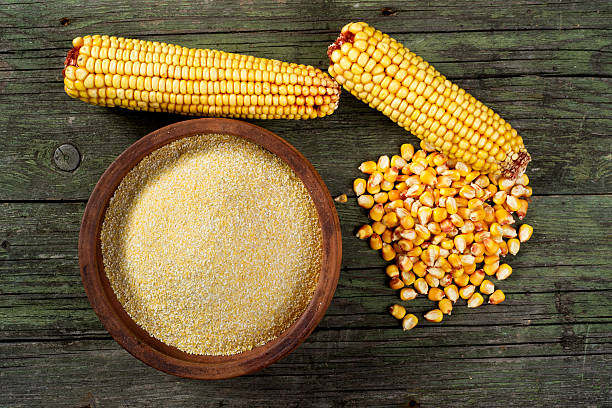 Maize, meal and ceramic bowl on wooden table stock photo