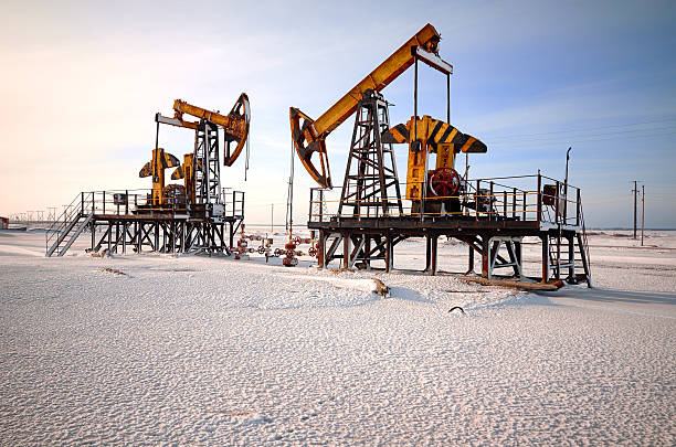 Oil rig back light Oil pump cold winter and snow. Back light, white cloudy and blue sky background, sunlight crude oil stock pictures, royalty-free photos & images