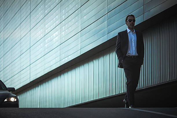 Handsome classy man in suit walks down the city street stock photo